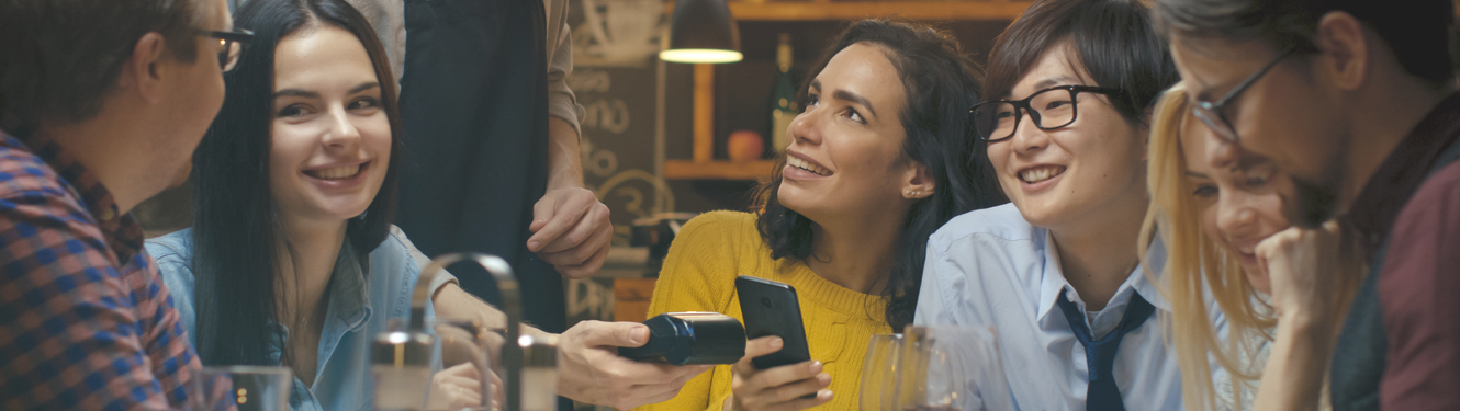 Group of people dining and using mobile pay