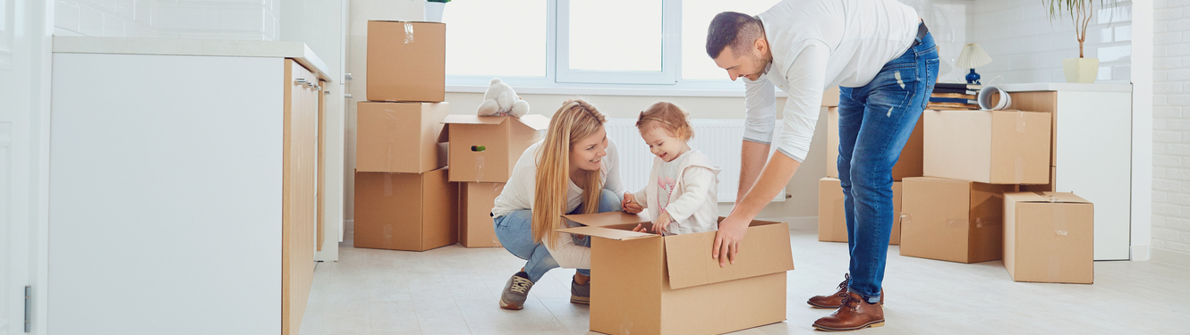 Mom and dad playing with child while moving with boxes.