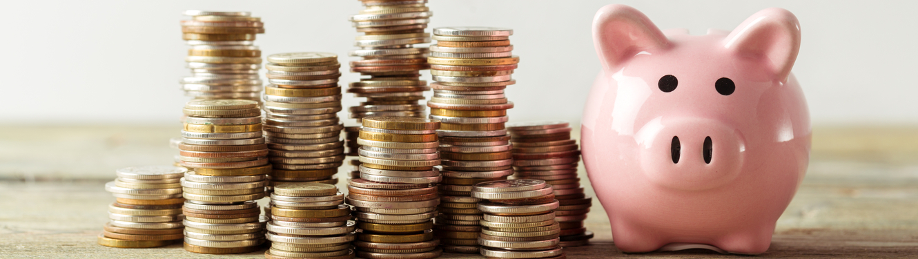 Stack of coins next to a Piggy Bank