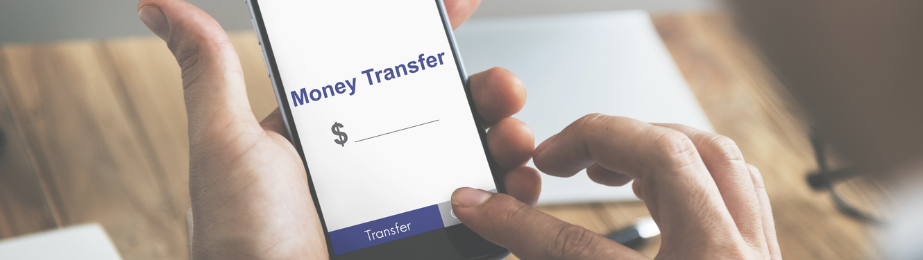 Man's hand holding a mobile phone with money transfer on it.